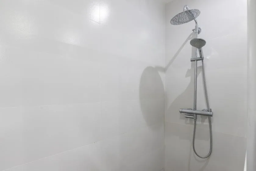 A shower with a large overhead showerhead against white walls.