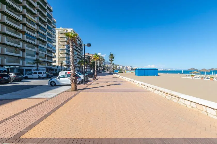 A seaside promenade runs beside apartment buildings, with the beach and sea visible to the right.