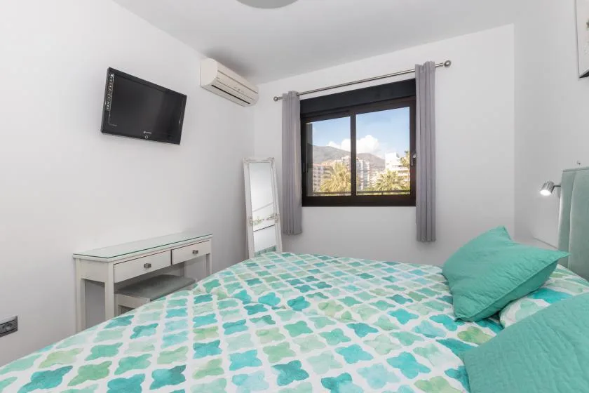 A bedroom with a bed covered in a turquoise-and-white patterned bedspread.