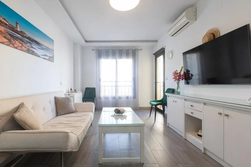 A bright living room with seating, a coffee table, and a television.