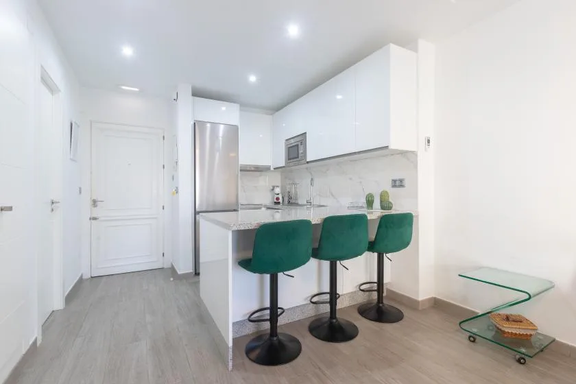 A bright modern kitchen has a counter with green bar seating.