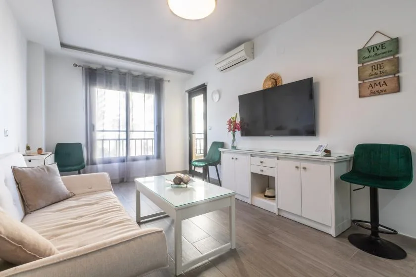 A bright living room with seating, a coffee table, and a television.