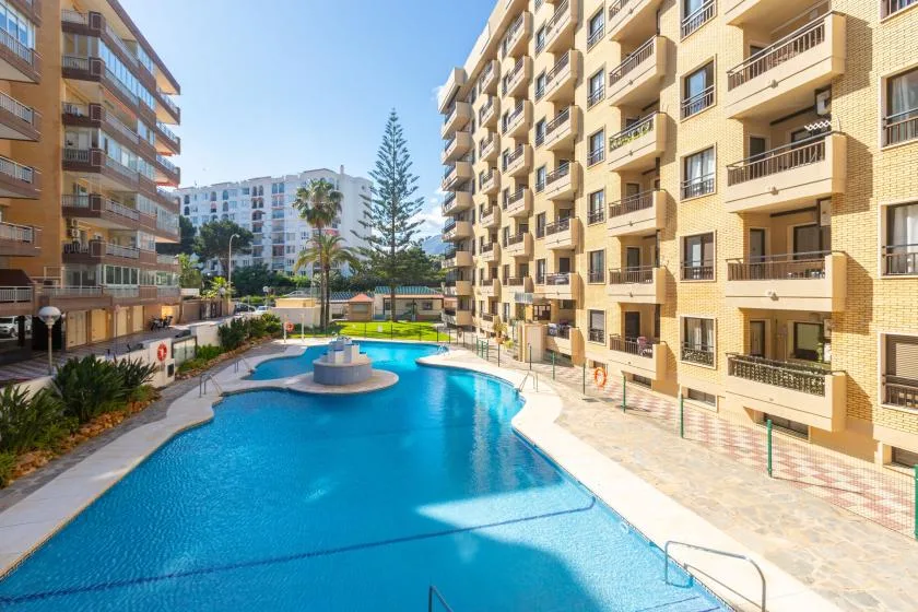 An outdoor swimming pool sits between several apartment buildings.