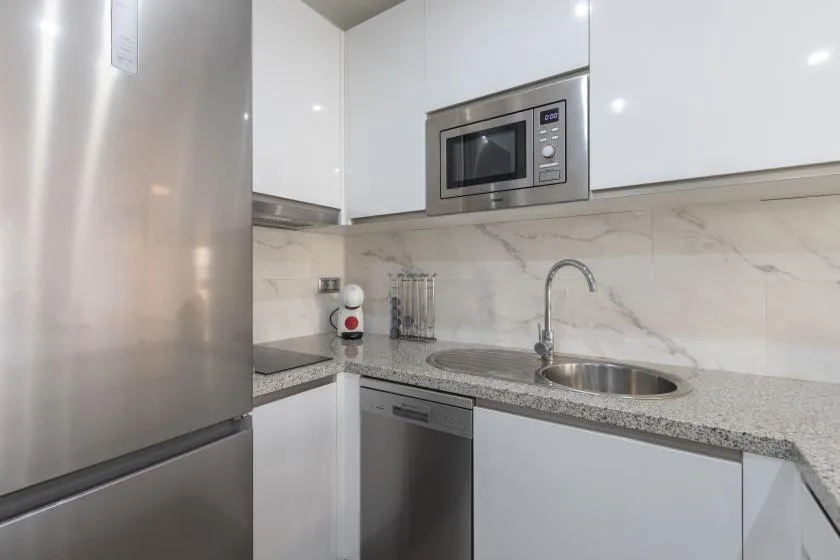 A compact kitchen with white cabinets, a microwave, and a sink.