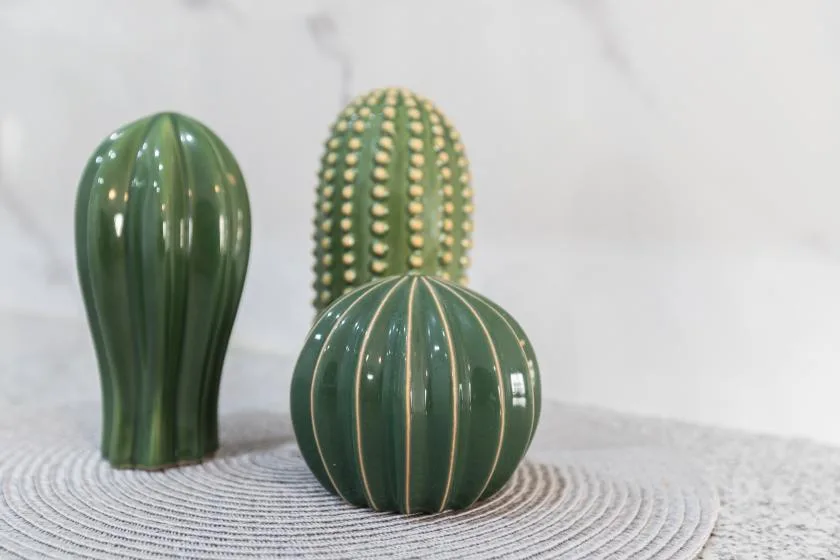 Three green cactus-shaped decorations sit on a round woven mat.