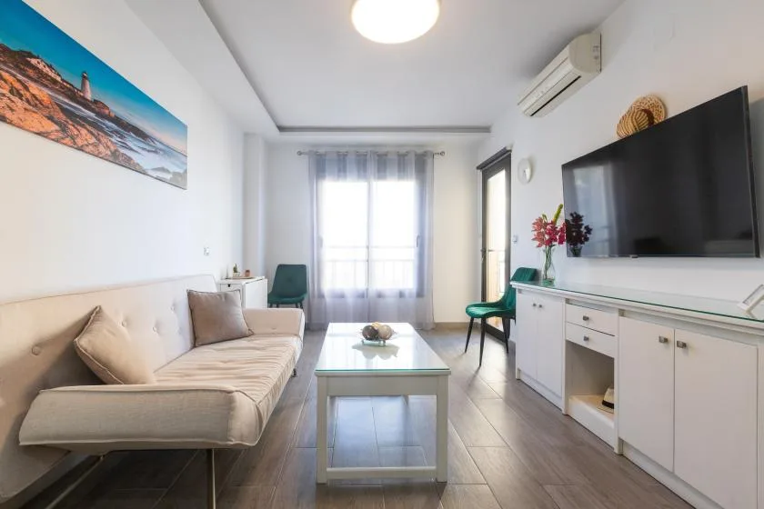 A bright living room with seating, a coffee table, and a television.