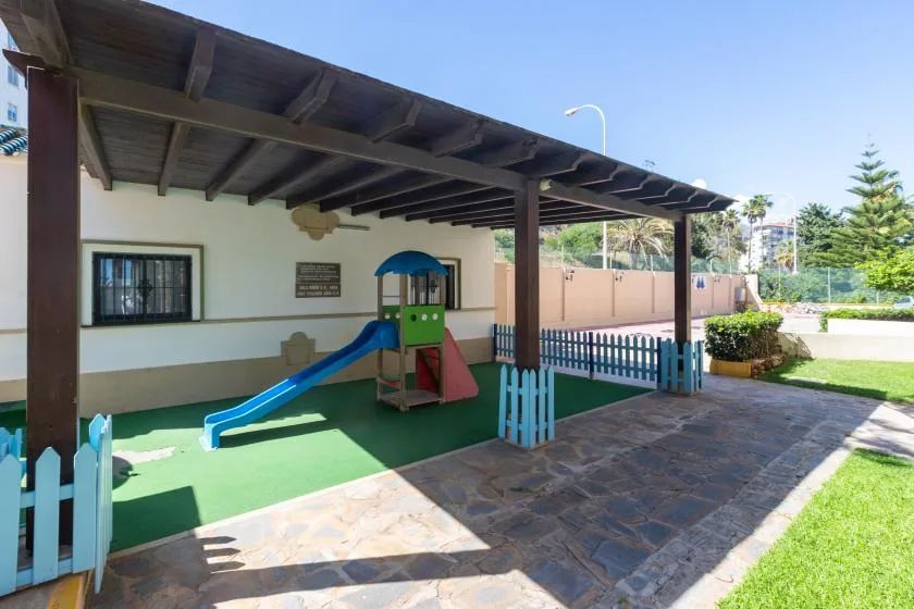 A covered outdoor play area with a small slide and climbing structure.