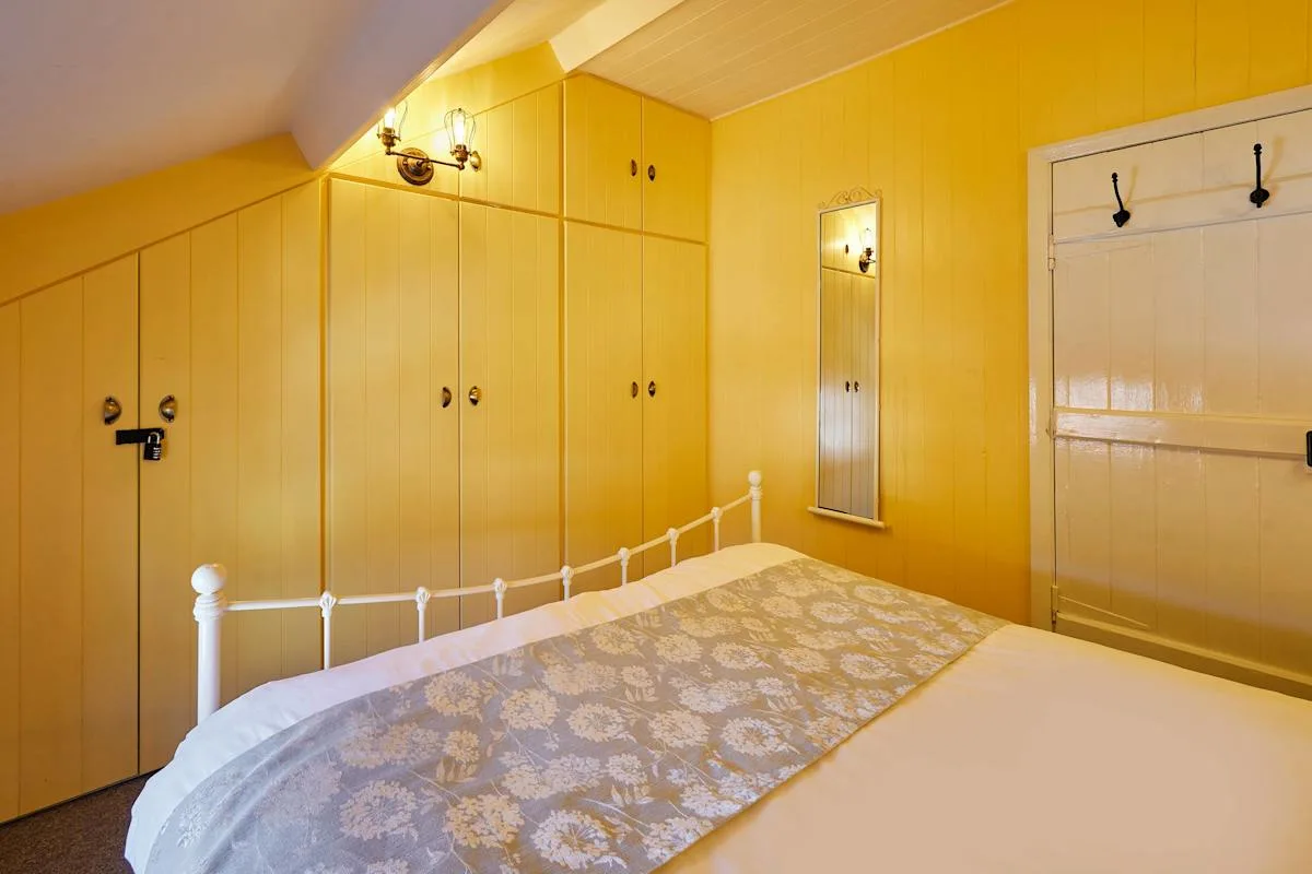 A bedroom with a bed, built-in wardrobes, and a wall mirror.