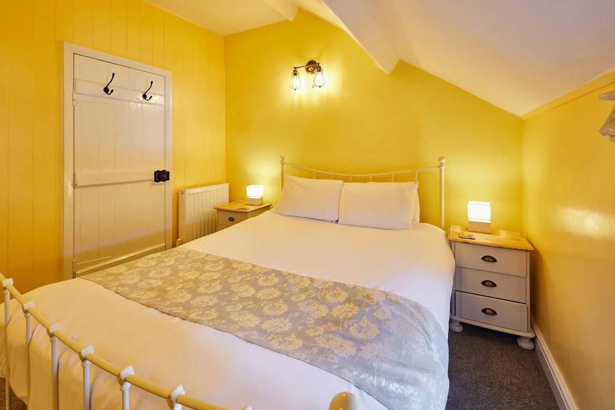 A bright bedroom with a white bed and yellow walls.