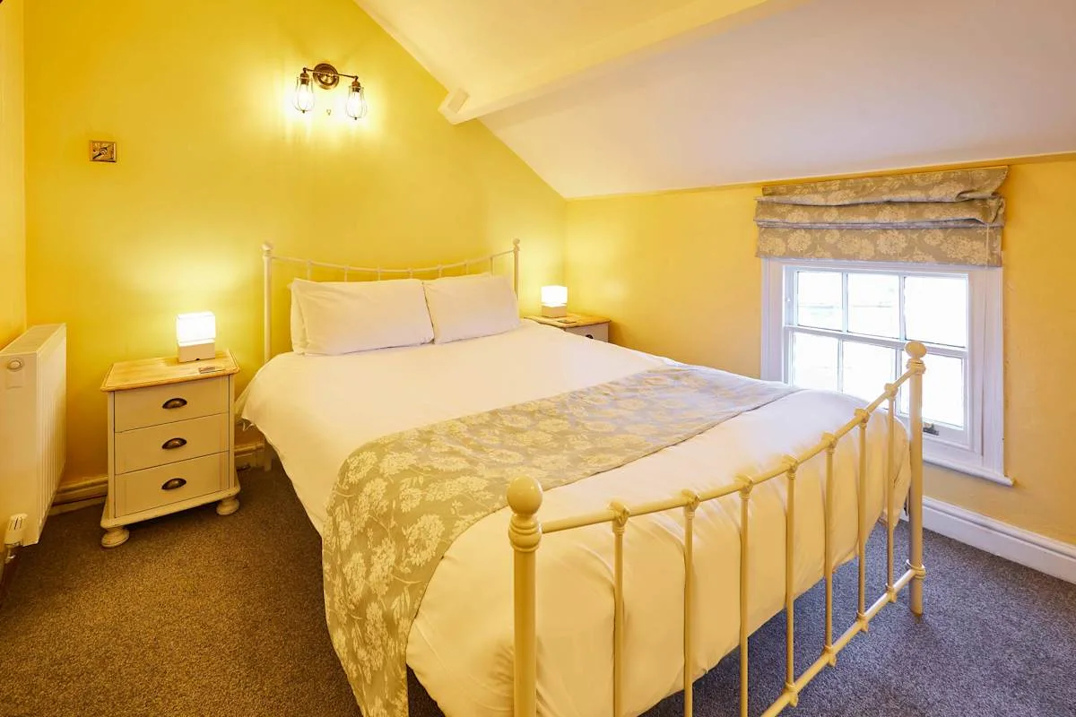 A bedroom with a metal bed, bedside tables, and a window.