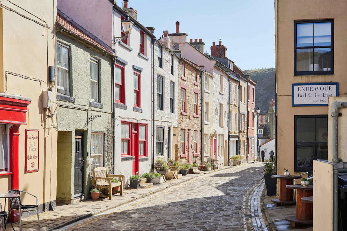 A cobbled street lined with colorful stone buildings and small storefronts.