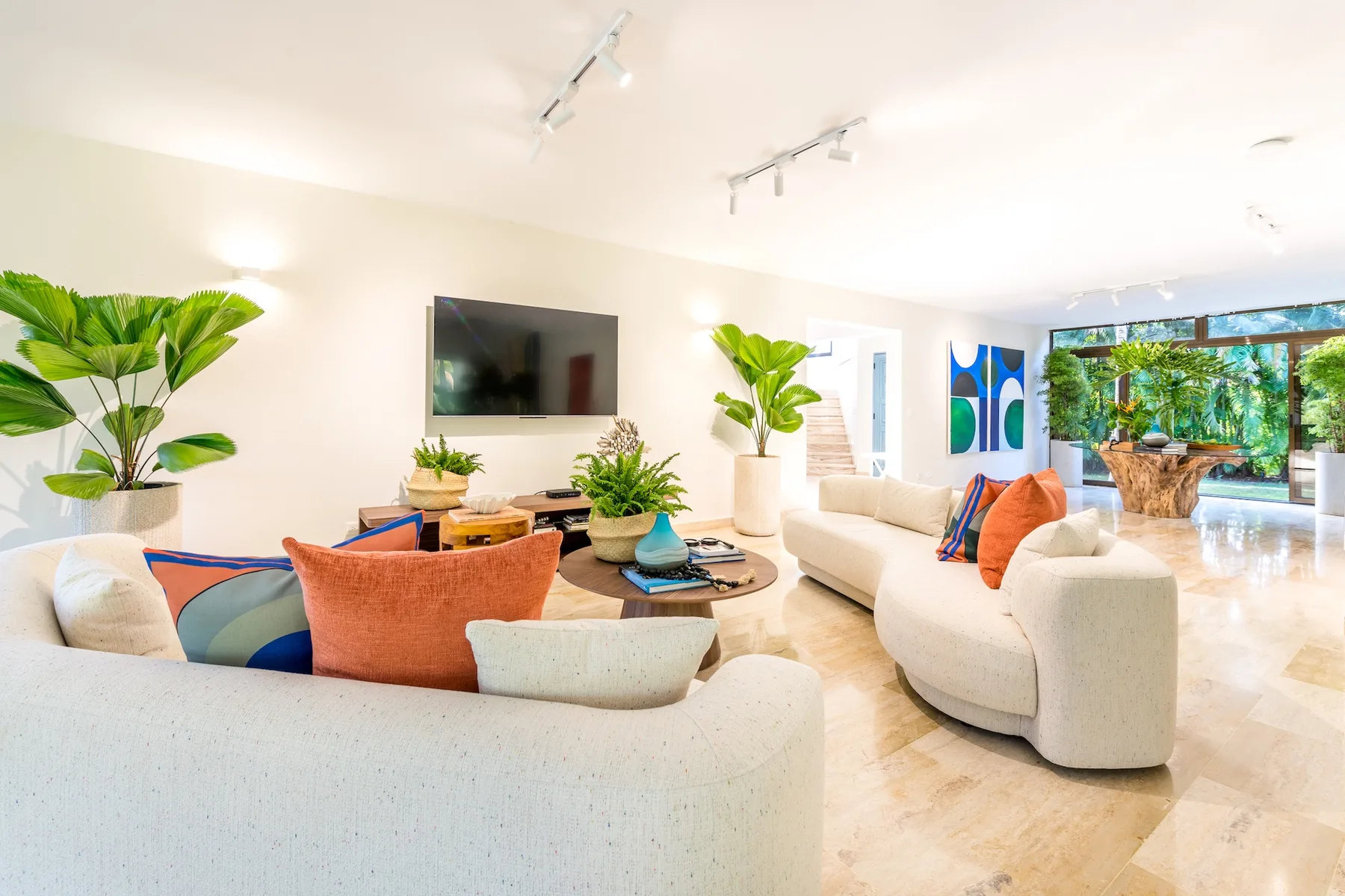 Una sala luminosa con asientos curvos, cojines coloridos y un televisor en la pared.