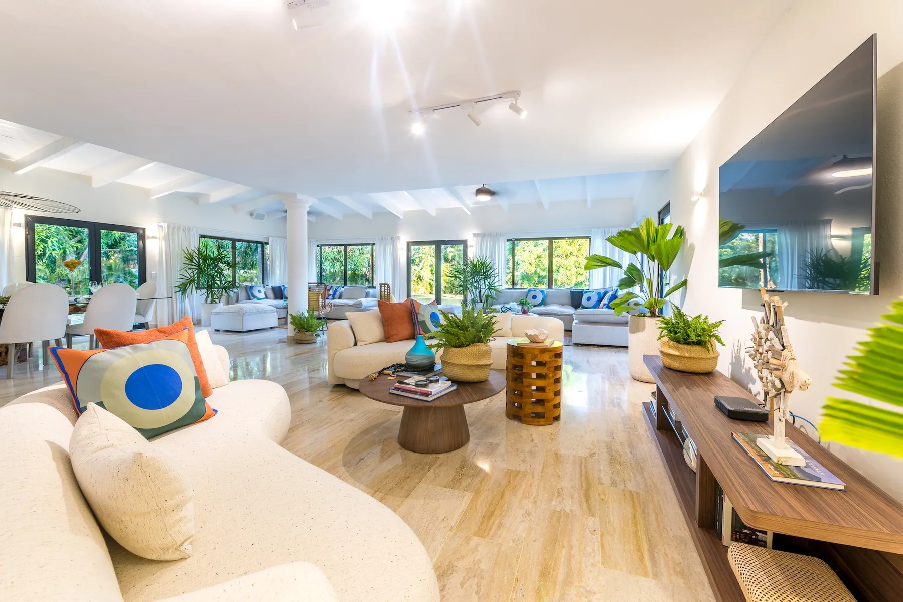 Una sala luminosa con asientos, una mesa de centro y ventanas grandes.