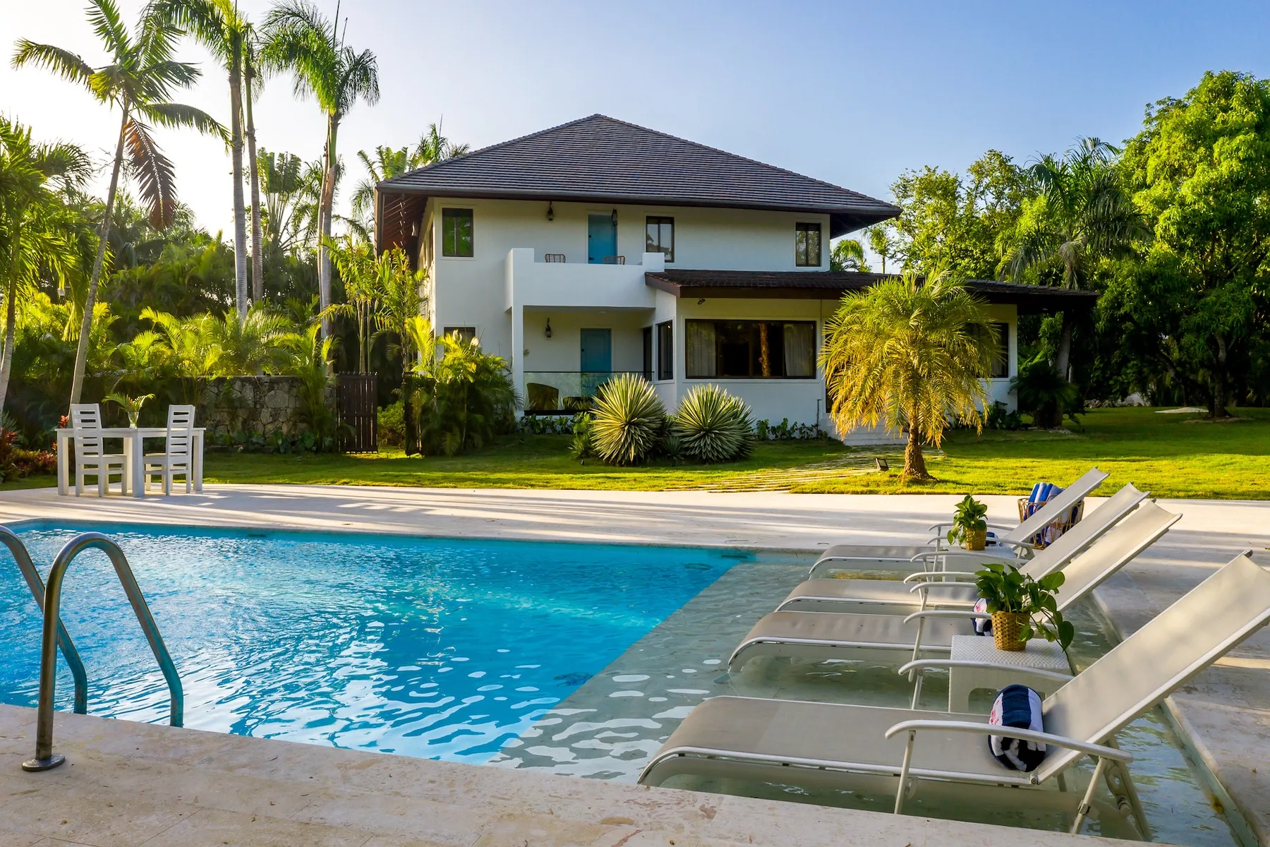 Una piscina al aire libre y asientos de descanso están frente a una casa moderna.