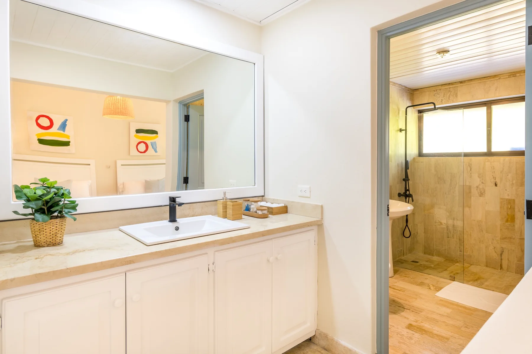 Un tocador de baño con lavabo y una ducha visible a través de la puerta.