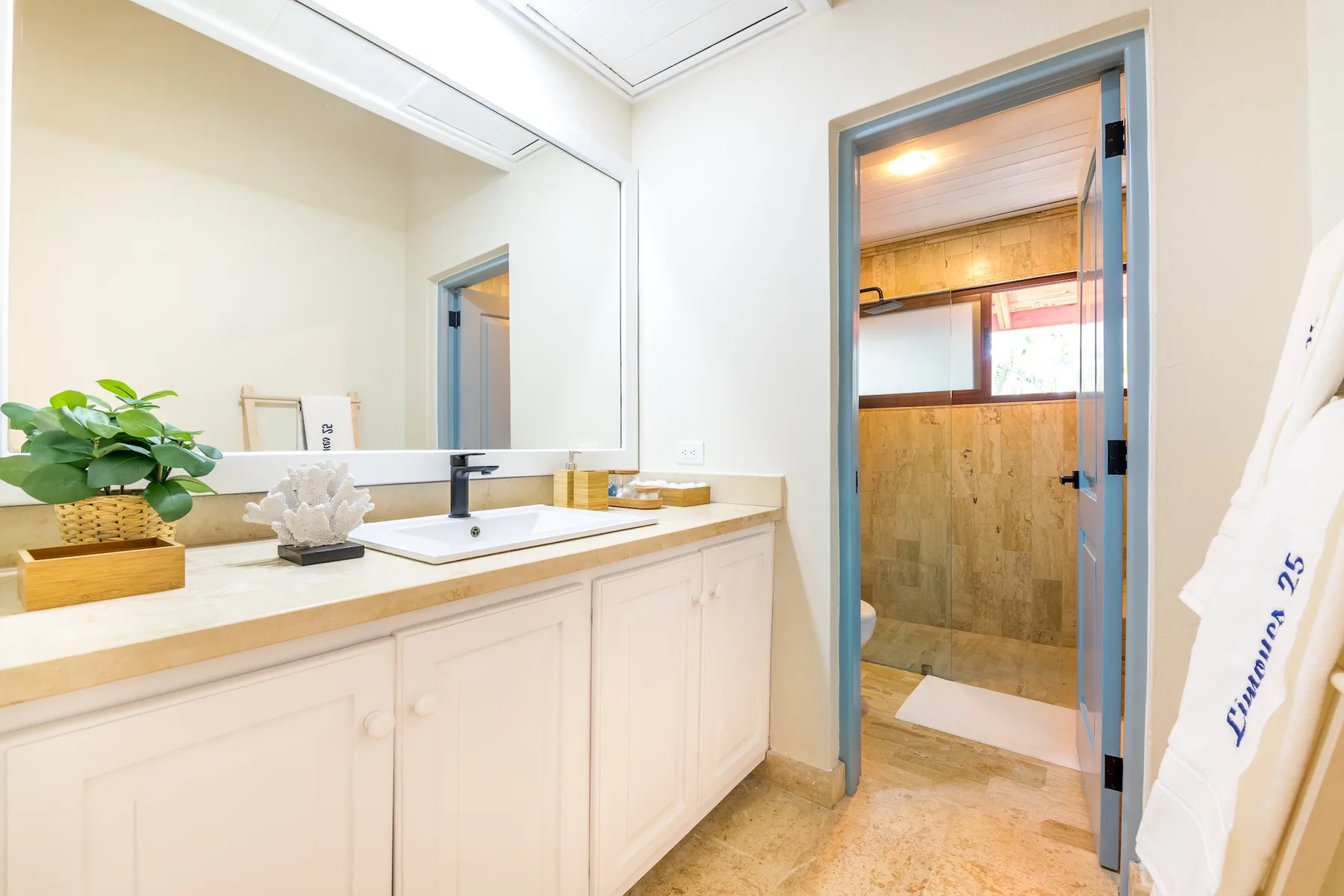 Un tocador de baño con un espejo amplio está junto a una ducha.