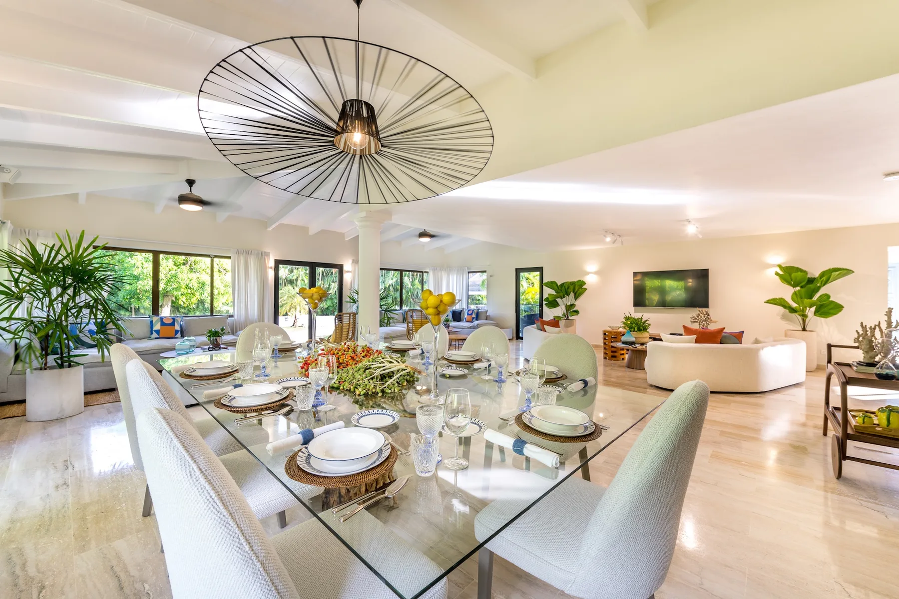 Un luminoso espacio abierto de comedor y sala incluye una mesa de vidrio y asientos.