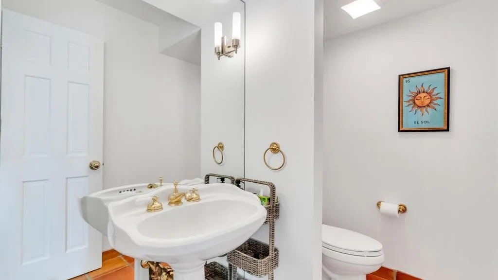 Un baño blanco cuenta con un lavabo de pedestal y un inodoro.