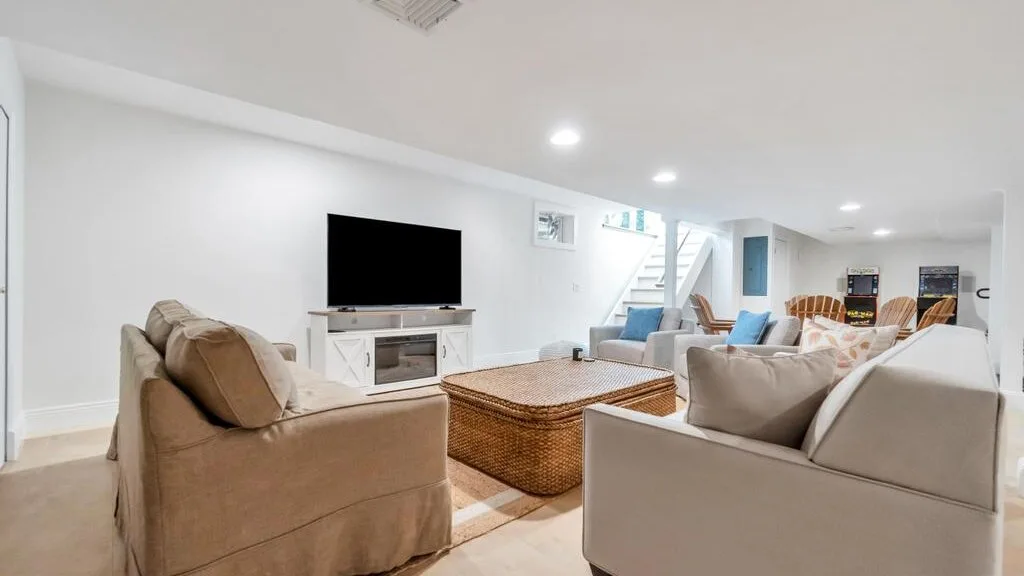 Una sala luminosa con asientos, un televisor y una mesa de centro tejida.