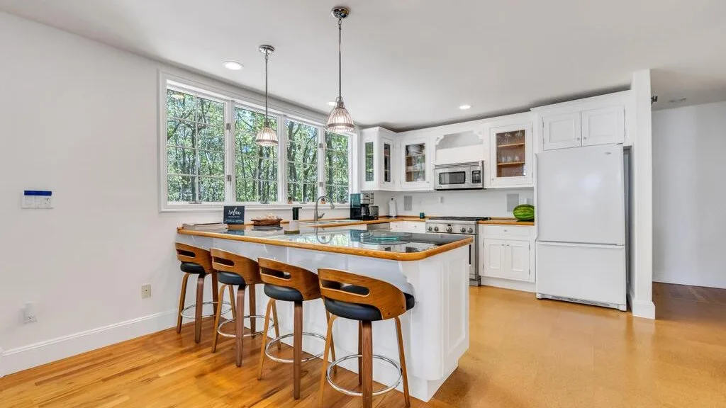 Una cocina luminosa con una isla central y ventanas grandes.