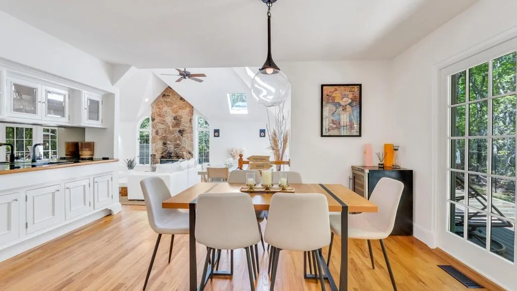 Un comedor luminoso con una mesa y sillas junto a grandes ventanas.