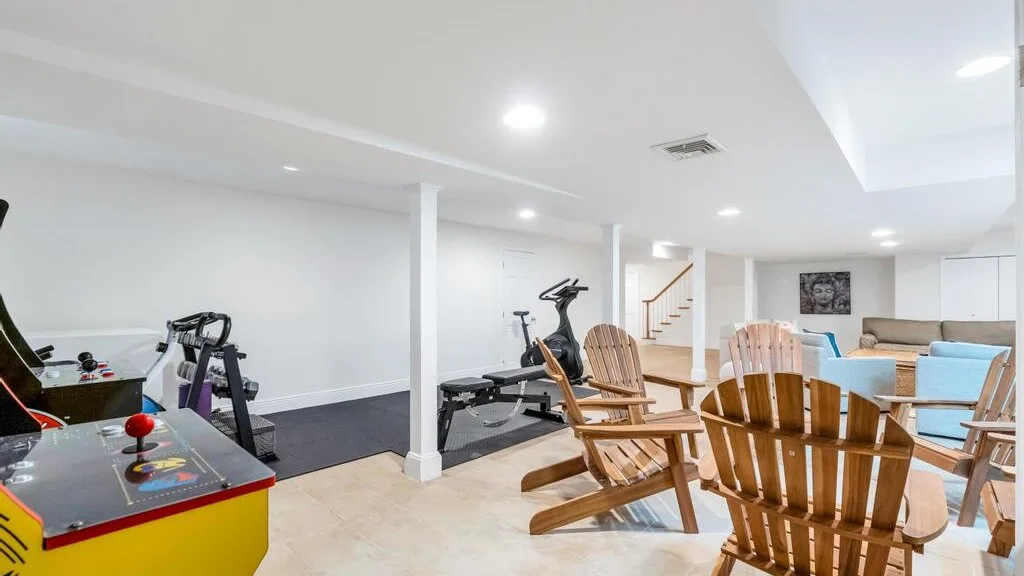 Una sala de recreación con equipo de ejercicio, asientos de madera y una mesa de comedor.