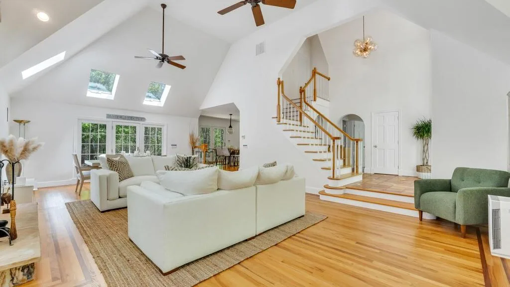Una sala luminosa con asientos blancos y una escalera.