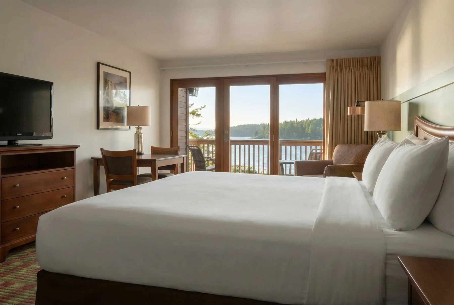 Guest room with bed and balcony overlooking water.