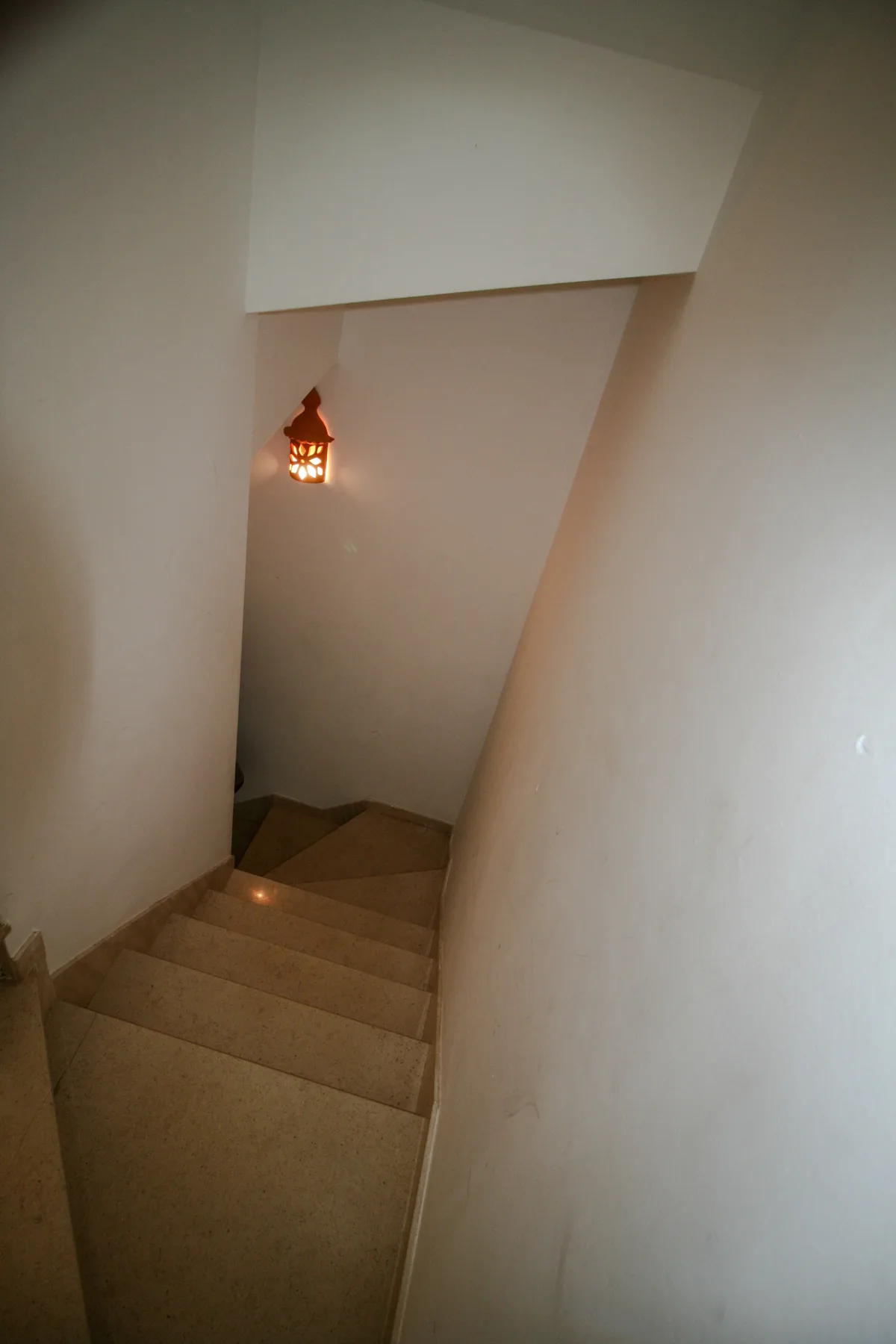 An indoor staircase descends beneath a small hanging light.