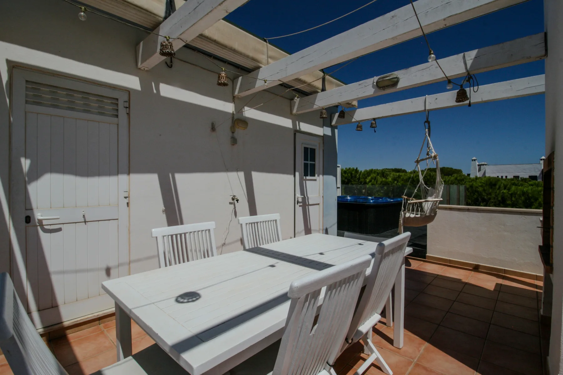 A rooftop terrace with a white dining table and outdoor seating.