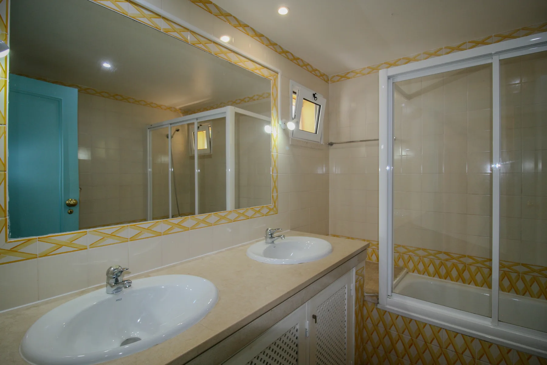 Un baño con un mueble largo, dos lavabos y puertas de ducha de vidrio.
