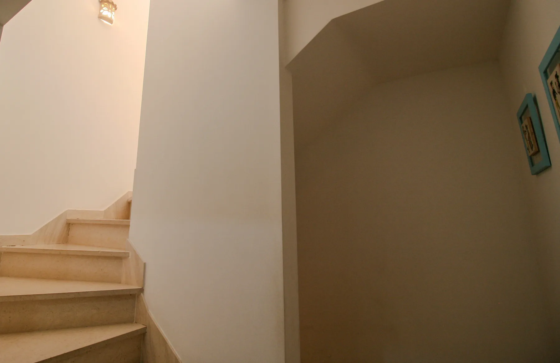 Interior stairway with light-colored steps and framed artwork on the wall.