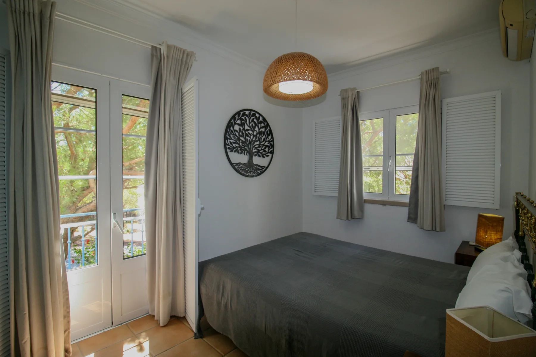 Un dormitorio con una cama, ventanas con cortinas y un adorno circular en la pared.