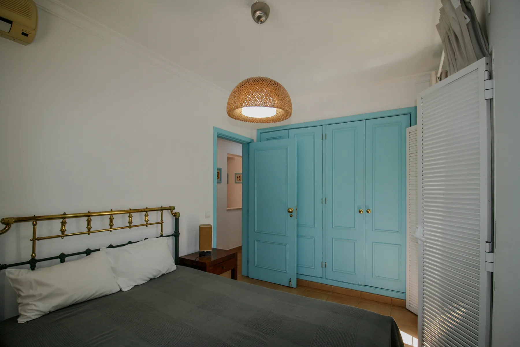 A bedroom with a bed beside turquoise built-in wardrobes.