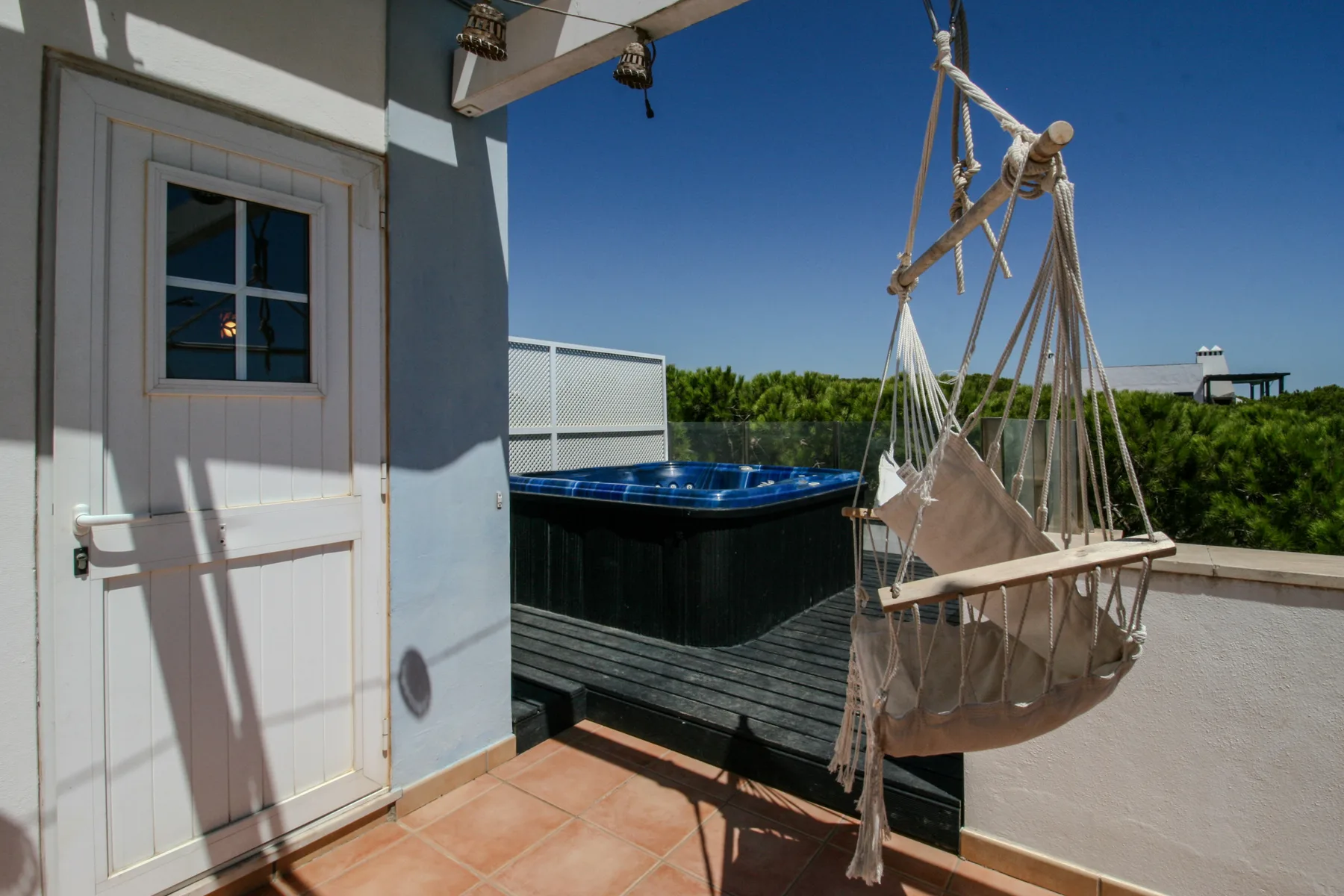 Terraza en la azotea con una bañera de hidromasaje exterior y una silla hamaca colgante.