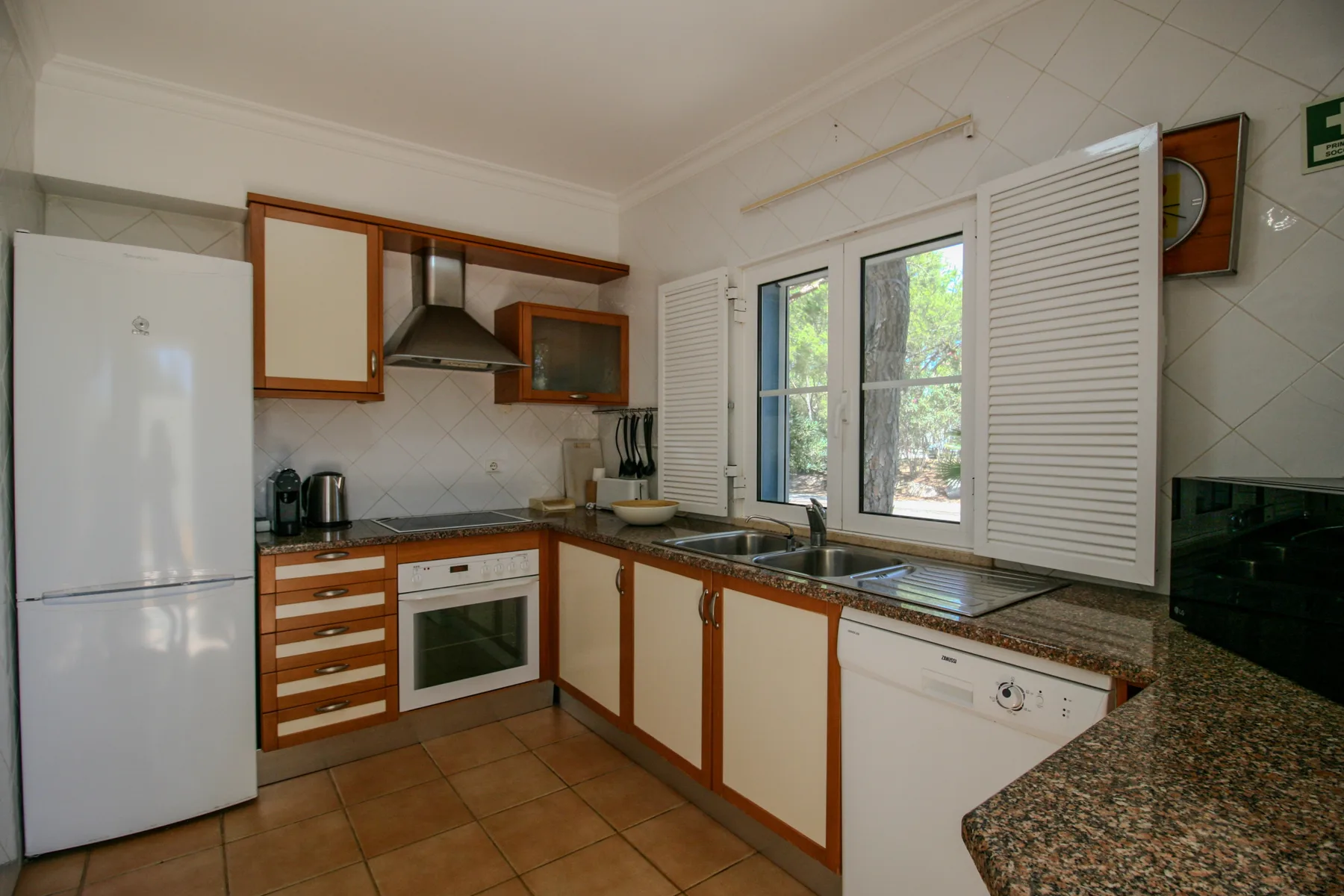 A kitchen with wood-trimmed cabinets and a window above the sink.