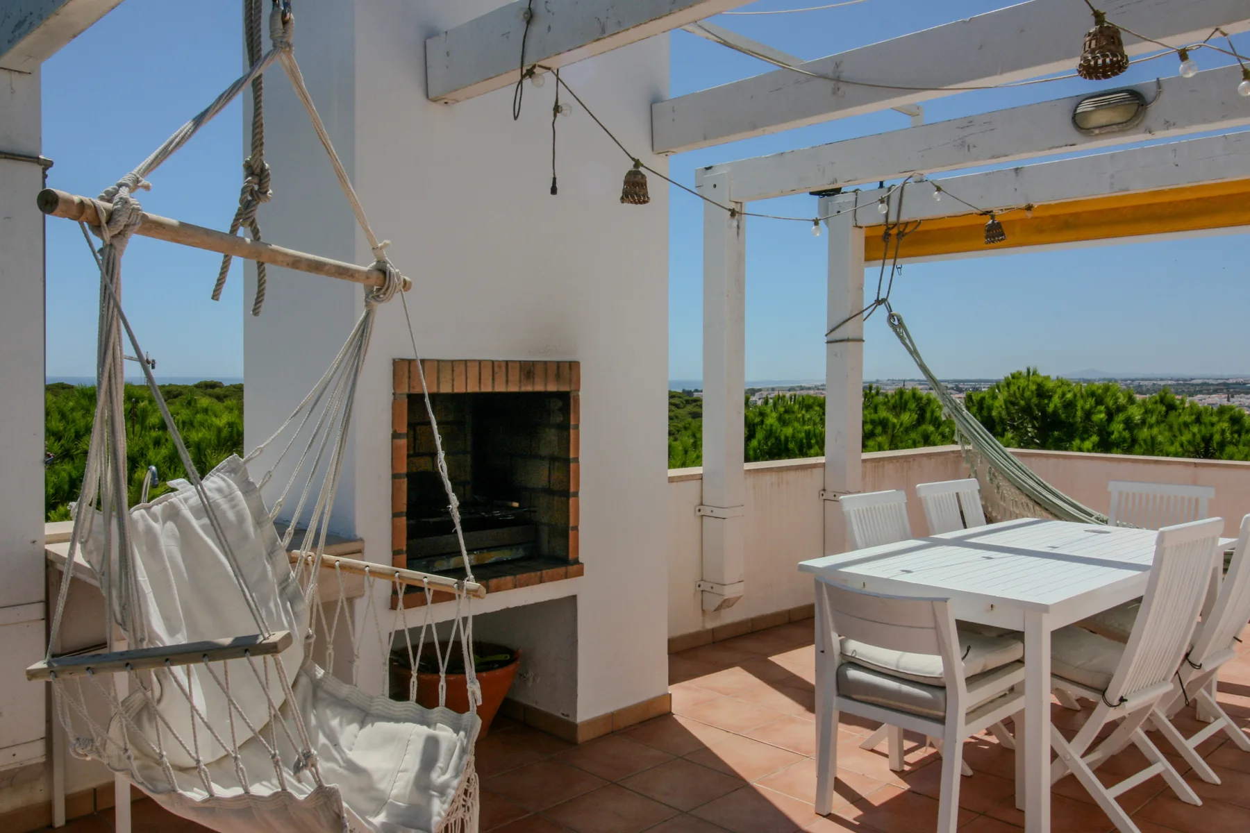 An outdoor dining and lounge area with a table, chairs, and hanging seats.