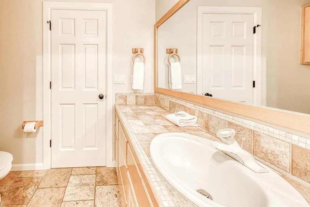 Un tocador de baño con lavabo, encimera y espejo de pared.