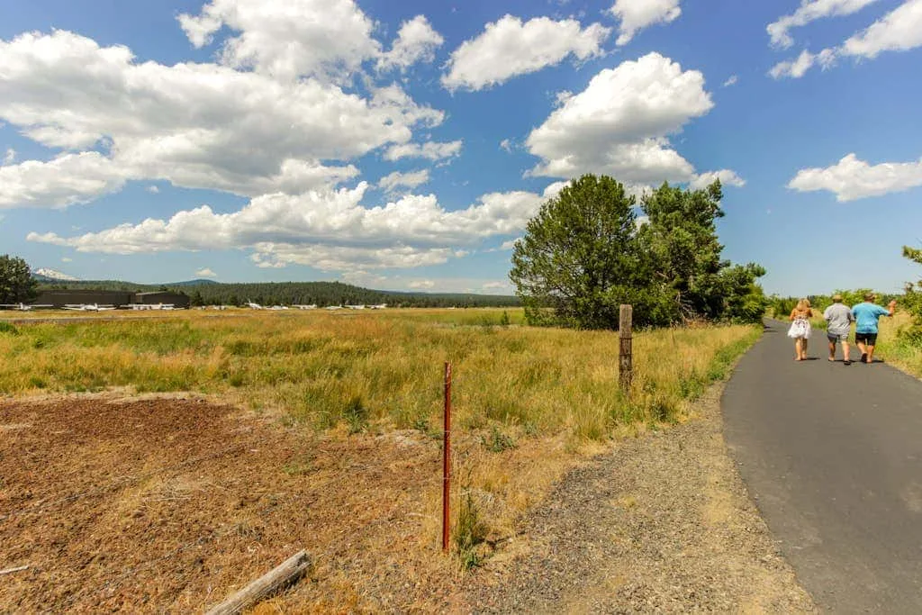 Un camino pavimentado bordea un campo abierto bajo un cielo nublado.