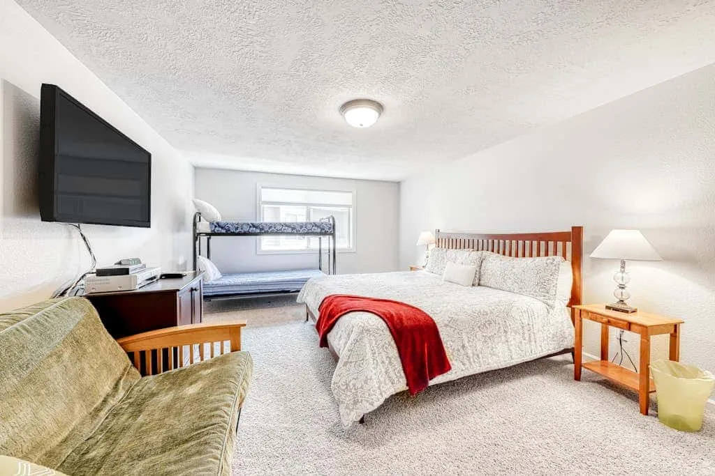 Un dormitorio con una cama grande, una litera y un televisor.