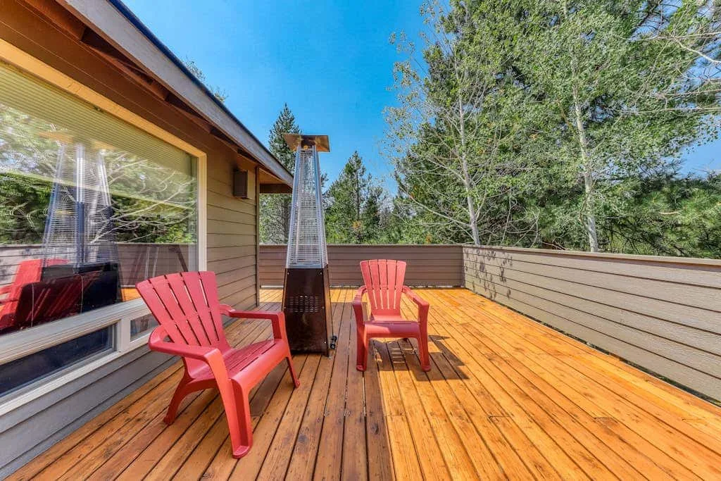 Una terraza de madera con asientos rojos y un calefactor de exterior alto.