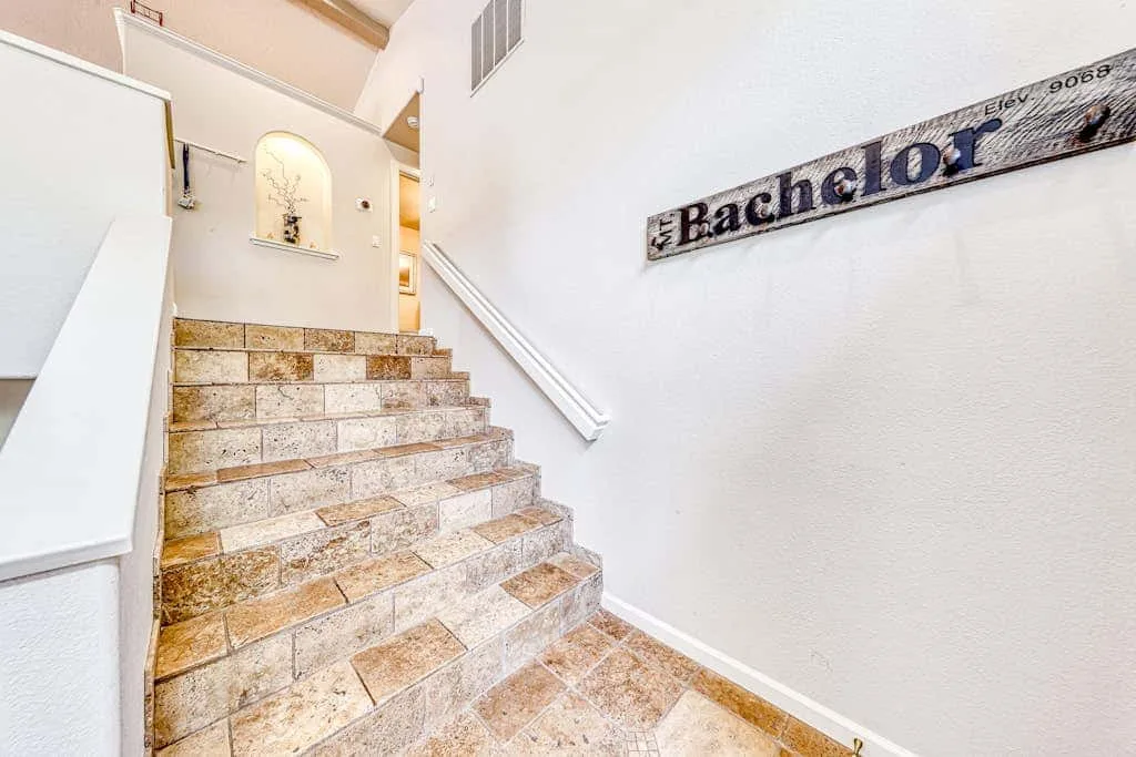 Una escalera de baldosas sube junto a una pared blanca con un letrero decorativo.