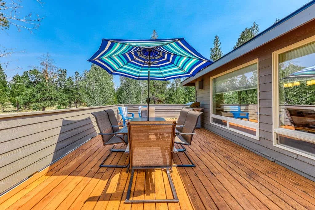 Una terraza exterior con asientos bajo una sombrilla azul a rayas.
