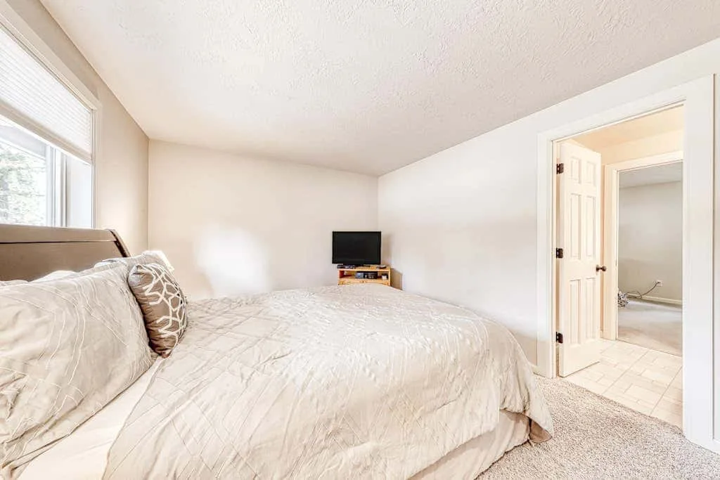 Un dormitorio con una cama, un televisor pequeño y una puerta abierta.