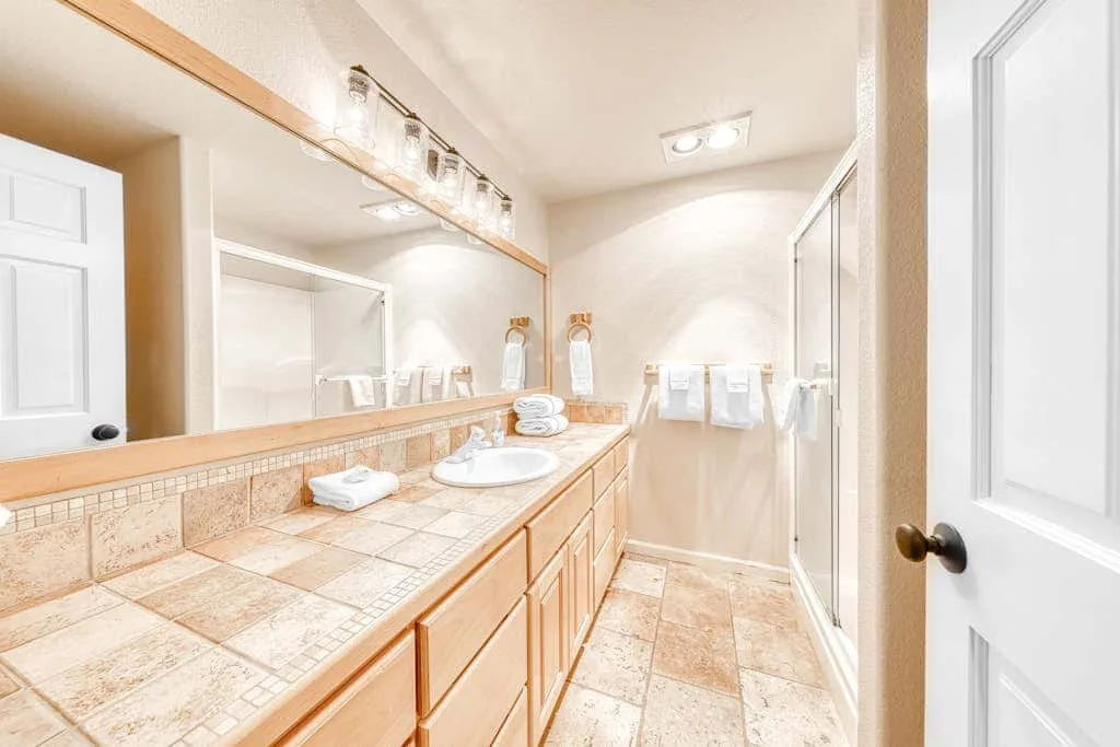 Un baño con un largo tocador de azulejos y una ducha de vidrio.