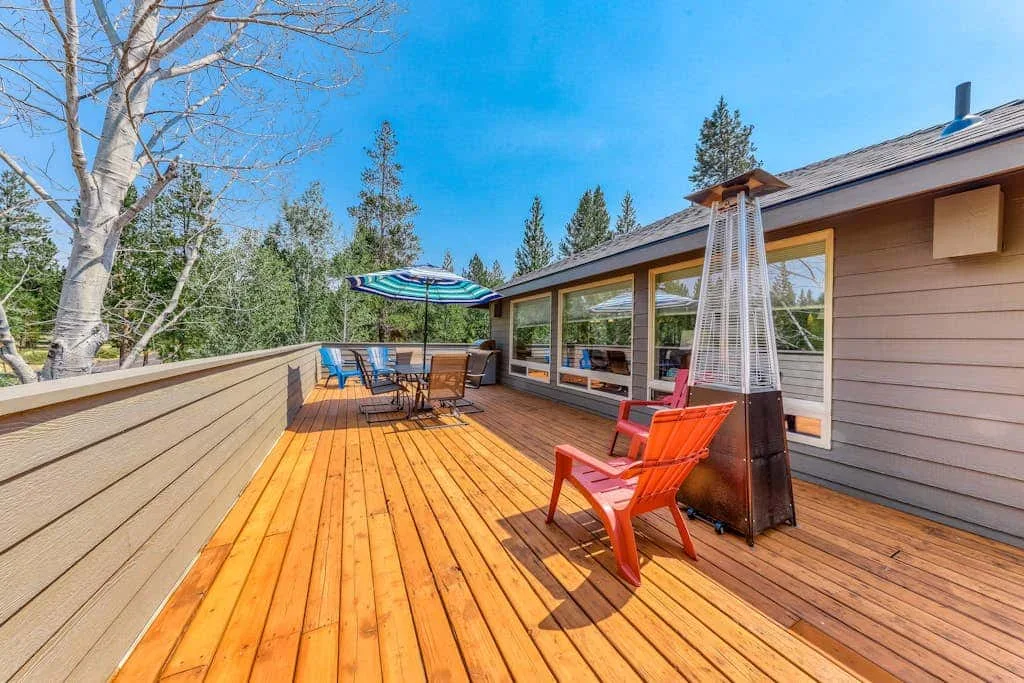 Una terraza de madera con asientos al aire libre y un calefactor junto a una casa.