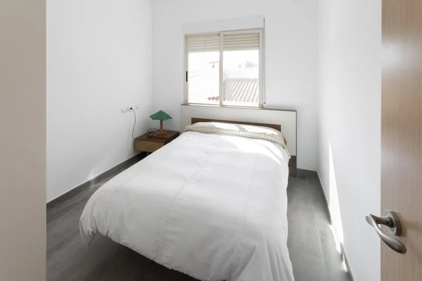Un dormitorio luminoso con una cama bajo una ventana.