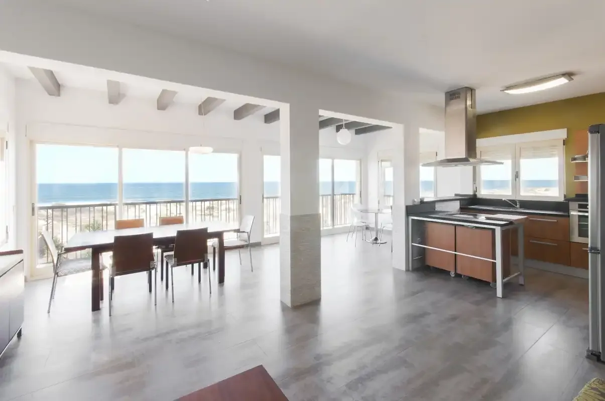Comedor y cocina de planta abierta con grandes ventanales con vistas al mar.