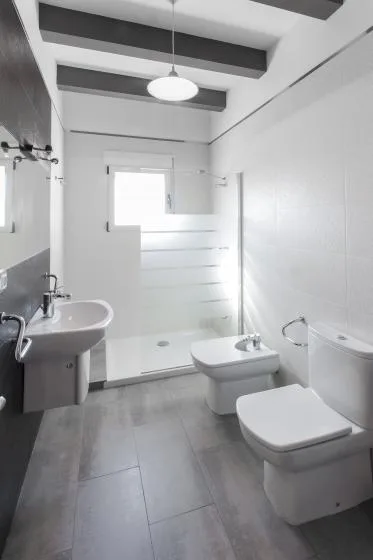 Un baño luminoso con lavabo, inodoro y zona de ducha de vidrio.