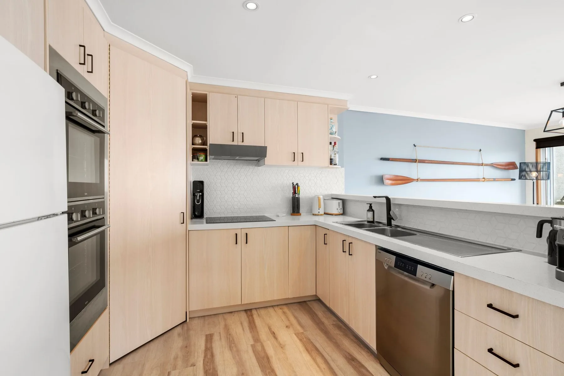 A bright kitchen with light wood cabinets and a long countertop.
